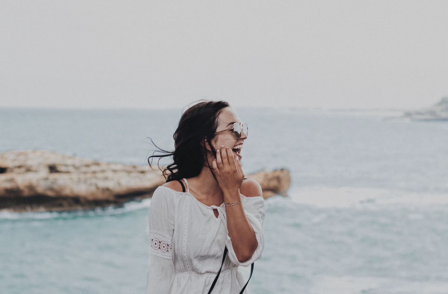 travel woman with sunglasses laughing on beach