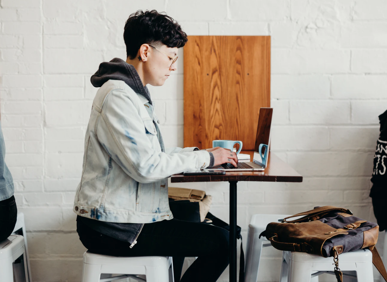 what is a scholarship , profile image of student in a jean jacket sitting in front of open laptop